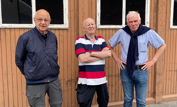Åke, Bosse och Björn – alla engagerade medlemmar i Kamratföreningen F8 – framför en gammal hangarbyggnad på outlet-området.
